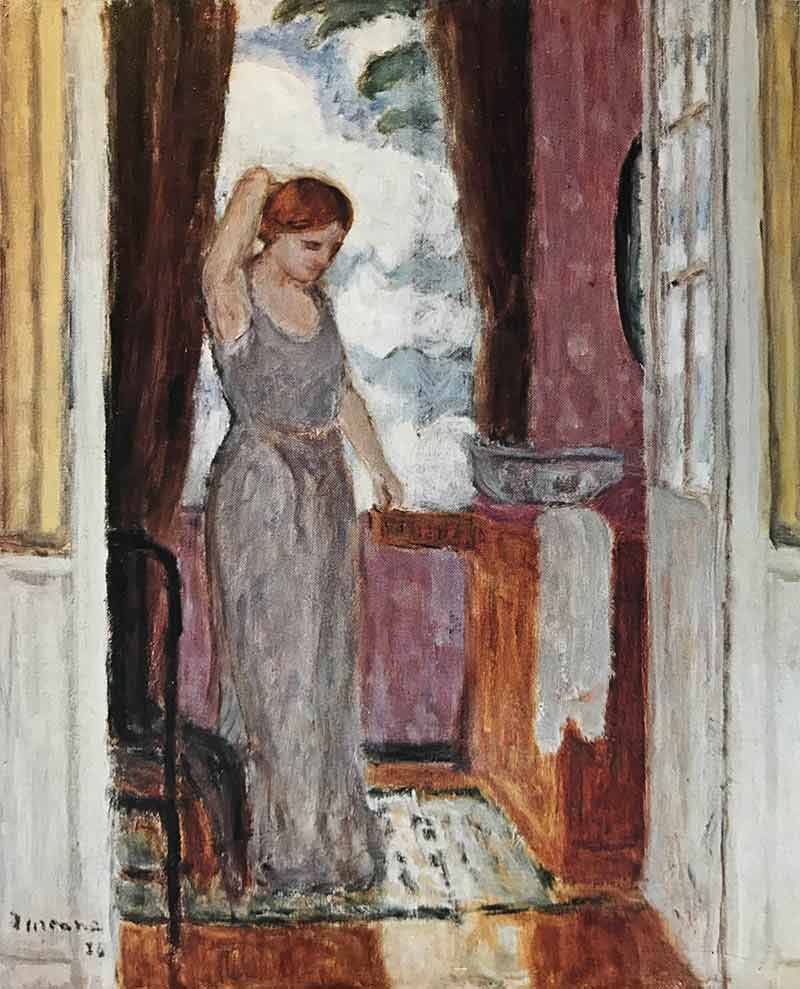 Red-haired woman in grey sleeveless outfit with right arm raised. Wash basin and towell to right of woman in front of open window. View through open doorway.